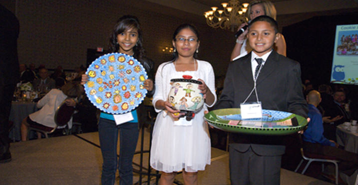 Alder Elementary Dreamers Abril Sierra, Giselle Amrosio and Jonathan Guerrero present the platters that Alder Dreamers designed for the Dream Big Live Auction. They are joined on stage by emcee Natali Marmion from KATU.