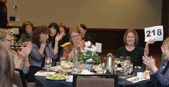 Jill Scott, Julene Siegel and Connie Medak bidding against each other to win the Painted Ladies quilt donated by Kathy Wheatley (far right)