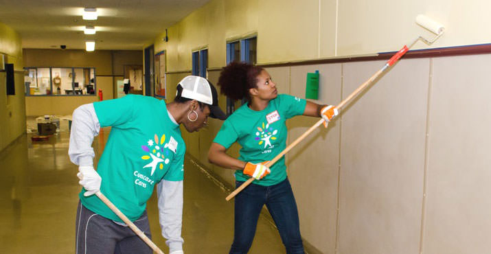 Guest volunteers Simi Adeagbo and Crystal Adams pair up to repaint a hallway inside Centennial Middle School. Photo by Aaron Hockley.