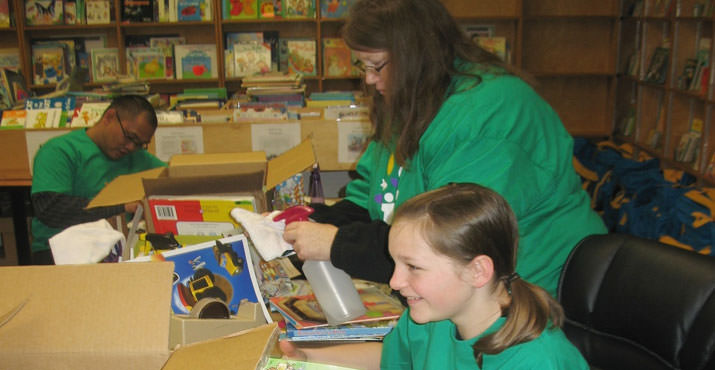 Comcast employee Bernard Lorenzo and guest volunteers Lisa and Sarah Ludwikoski clean, repair and sort books at the Children's Book Bank. Photo by Robert Negrete.