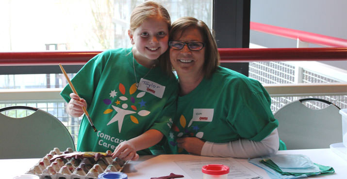 Comcast employee Vicki Klein and granddaughter Taylor Menard man the fish printing station at OMSI. Photo by Rosemarie Cordell.