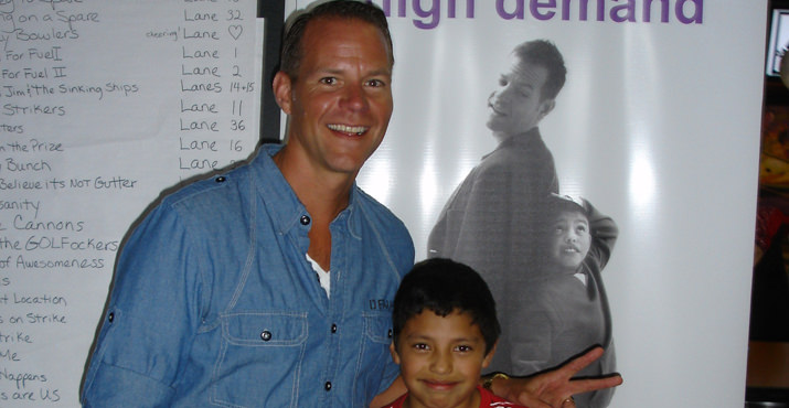 Tim Hershey, Nike and Big Brothers Big Sisters board member, stands with his Little Brother Felix in front of a banner displaying their image