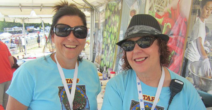 Annie Herbet, Director of Communications, and Jean Kempe-Ware, Public Relations Manager, smile together near the entrance of the event where over 104,000 pounds of food was collected.