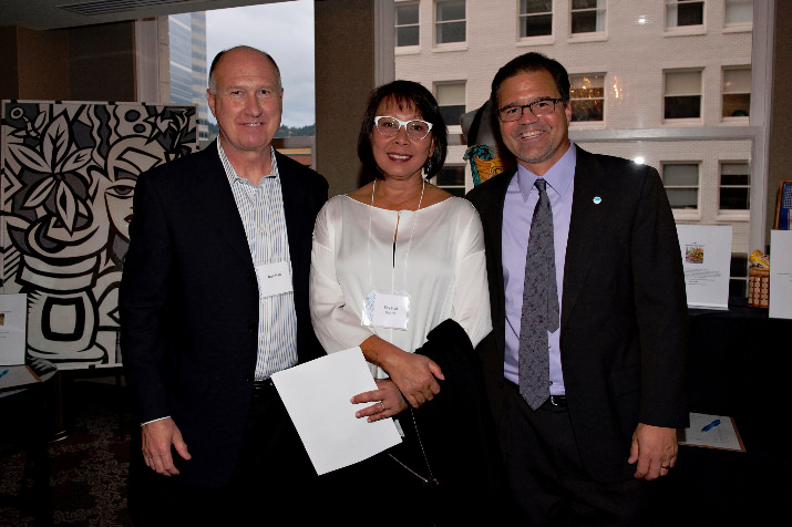 Board Member Kay Hall with her husband Dan Hall and “I Have a Dream” President & CEO Mark Langseth smile for the camera in front of art from famed artist Tom Cramer during the social hour