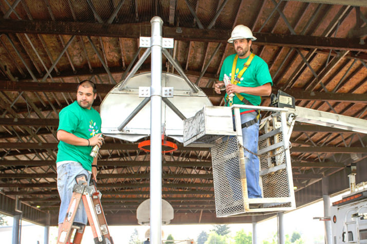 Comcast technicians Neil Edge and Nathan Pancoast spray-paint a basketball hoop at Faubion School. Photo by Andie Petkus.