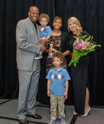 Craig Robinson, Head Men's Basketball Coach at Oregon State University, holds one of his two young sons. He is pictured with his daughter Leslie Robinson, (center) and wife, big brother of first lady Michelle Obama, who mentioned in her interview for a video for the celebration that because her father had passed at the time she married Barack Obama, it was Craig Robinson who walked her down the aisle. her protector Kelly Robinson a mentor and motivator, His wife