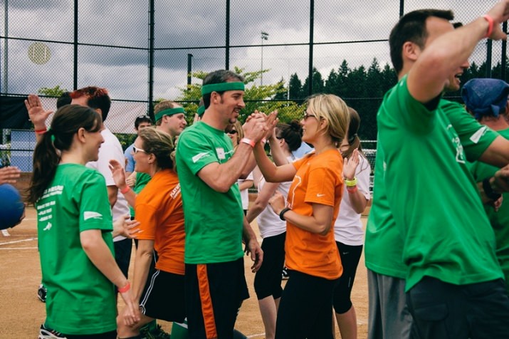 Team Schwabe, Williamson & Wyatt (green shirts) and Team hubbub health (white and orange shirts) start the game with high-fives.