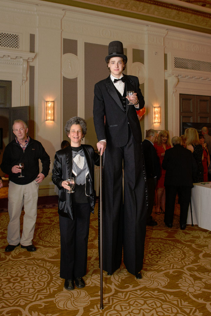 Jean Rystrom accompanies her son as he makes his way around the silent auction on his stilts.