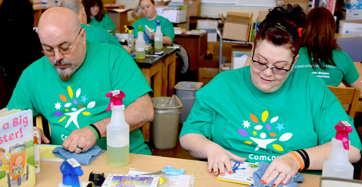 Arthur and Comcast employee Angelique King wipe down books to prepare for donation by the Children's Book Bank. Photo by Wendy Rectenwald.