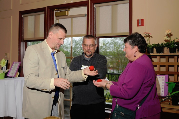 Magician Dan Waterman (left) dazzles Karen Wegener while her husband Brian Wegener (center) looks on.