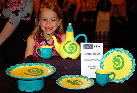 Hailey, a Dougy Center Kid, shows off her artwork in the silent auction