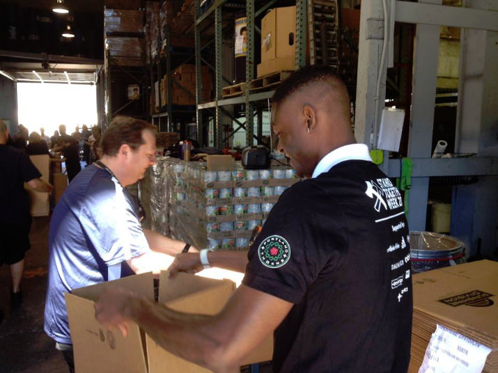 Fanendo Adi and Alaska Airlines help clean and pack food for local families at Portland Police Bureau Sunshine Division during Stand Together Week. Photo, Portland Timbers