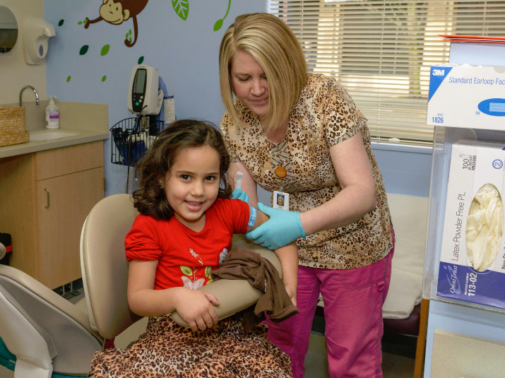 Hager Arheim, 5, is all smiles as registered nurse Dawn Sorensen prepares to give her a vaccination at one of Kaiser Permanente Northwest’s seven free Give Kids a Smile clinics on February 7. Credit: Andie Petkus Photography 