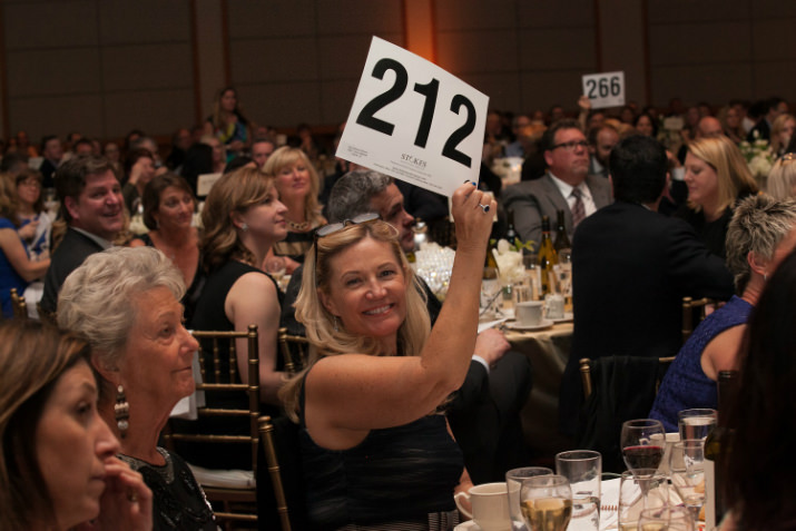 St. Mary's Academy benefactor Mary Mathews Stevens '80 raises her paddle for the school