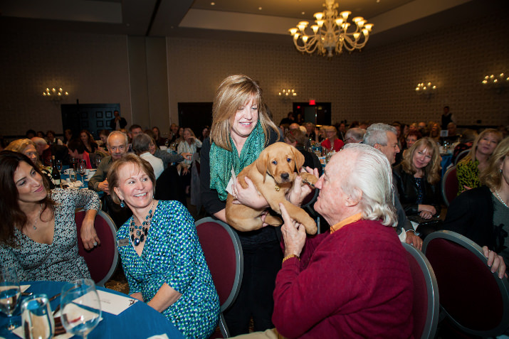 Christine Benninger, the CEO of the nonprofit, sits with local philanthropist and long-time GDB supporter Howard Hedinger as he meets a puppy in training.