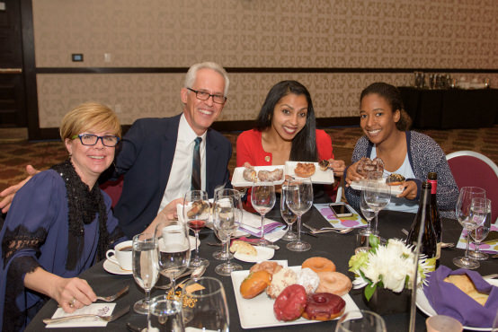 Raphael House of Portland Board Members Rick Lesniak (second from left) and Marguerite Matthews (third from left) join their table in enjoying a selection of Blue Star Donuts won during the Dessert Dash.