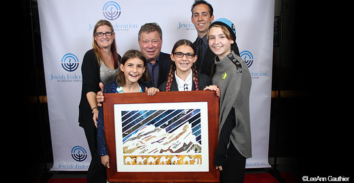 Isaac Brynjegard-Bialik and family present his mixed media piece, "To Boldly Go" to William Shatner. The artwork is made of strips of Star Trek comics.