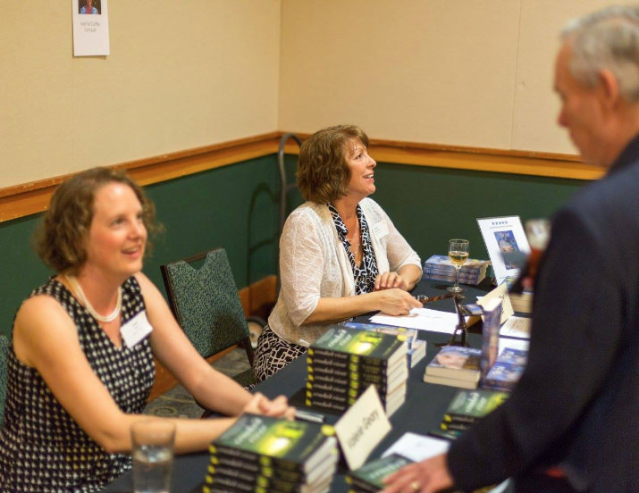 Marcia Turnquist signs a copy of her novel, "The God of Sno Cone Blue". The author and journalist, is currently writing her second novel, Skipping the Light.