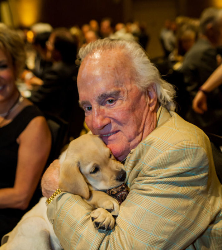 Portland philanthropist and long-time GDB supporter Howard Hedinger cuddles a future guide dog
