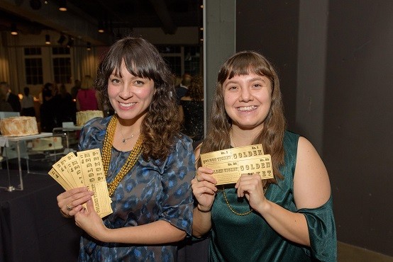 Raphael House of Portland staff Karla Viteri (left) and Jordan Hernandez (right) sell Golden Tickets that give buyers a 1/100 chance of winning the live auction package of their choice.