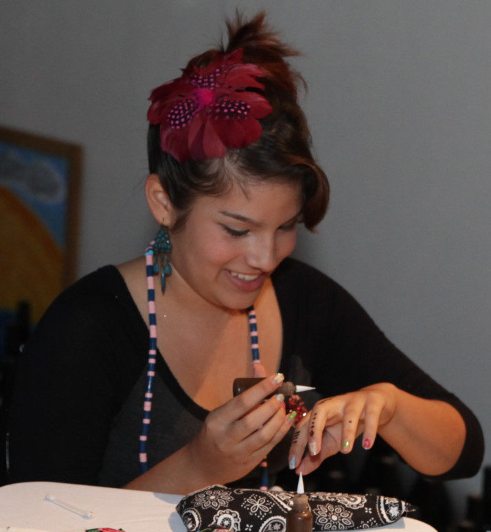 Stella M, featured artist at the first CHAPlandia event (in 2012), prepares for volunteer henna shift by practicing on her own hand.