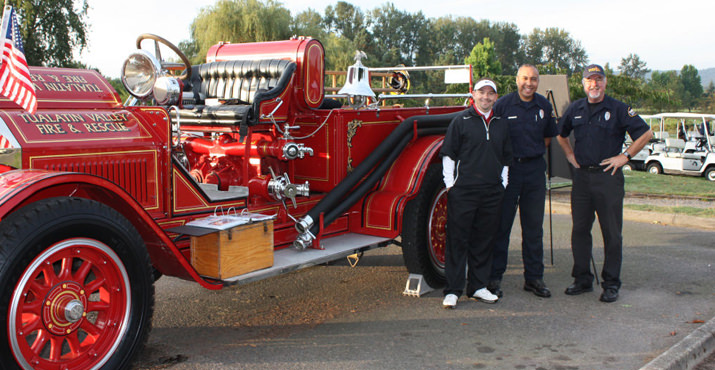 Jeff Cutis, CEO Rose Festival Foundation, stands with BC Richard Block and Guy Haynes next to the tournament center piece: a vintage fire truck on loan from Tualatin Valley Fire & Rescue.