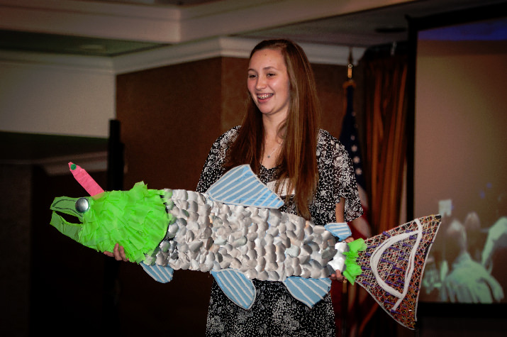 Gladstone High School student, Emily Doll, displays trash artwork pieces she created during the live auction.