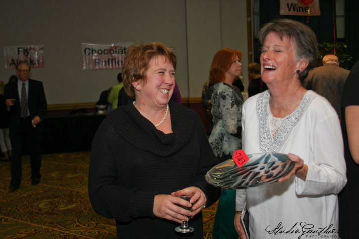 Victoria Purvine admires a glass bowl made by presenting sponsor Alyson Huntting. Huntting bought an outdoor address base mount donated by Purvine’s company Evergreen Remodeling, Inc.